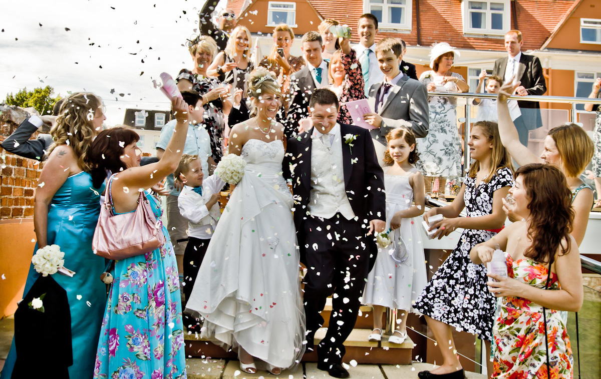 Wedding party celebrating and throwing confetti at the bride and groom